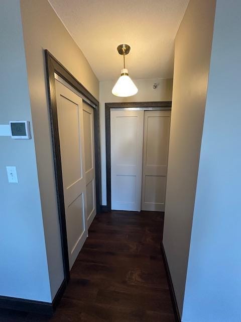 hallway featuring dark wood-style floors and baseboards