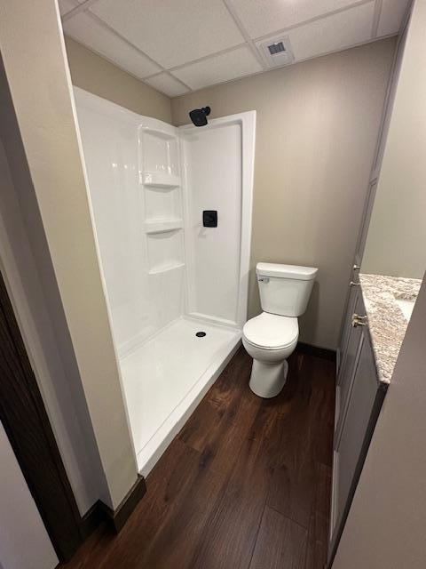 bathroom with visible vents, a drop ceiling, toilet, wood finished floors, and a shower stall