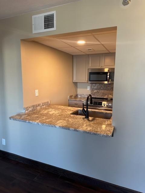 kitchen featuring stainless steel appliances, a paneled ceiling, a peninsula, and visible vents