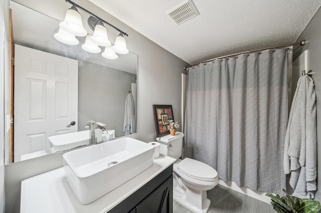 full bath featuring vanity, visible vents, a textured ceiling, curtained shower, and toilet