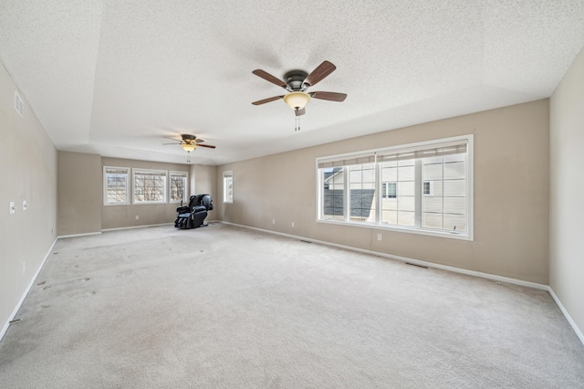 unfurnished living room featuring visible vents, a ceiling fan, a textured ceiling, carpet flooring, and baseboards