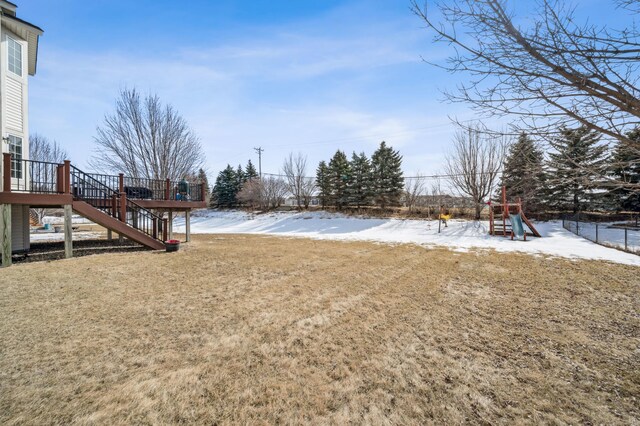 yard layered in snow featuring stairway, playground community, and a wooden deck