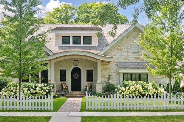 view of front of property featuring stone siding and roof with shingles