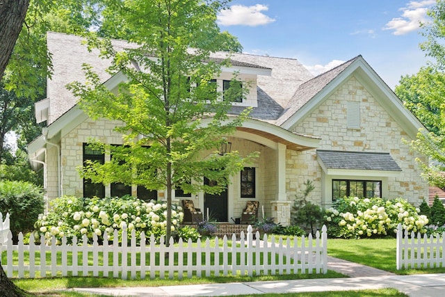 view of front of house featuring a front lawn, fence, and roof with shingles