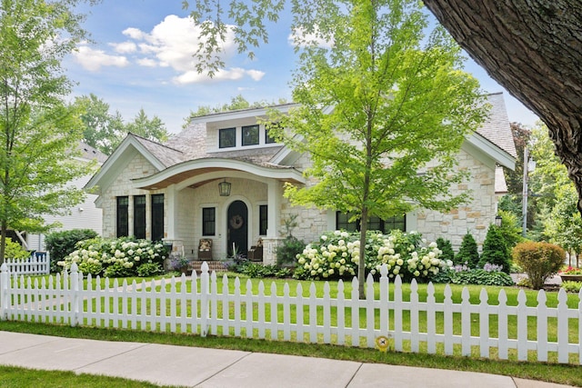 view of front facade with a fenced front yard, stone siding, and a front yard