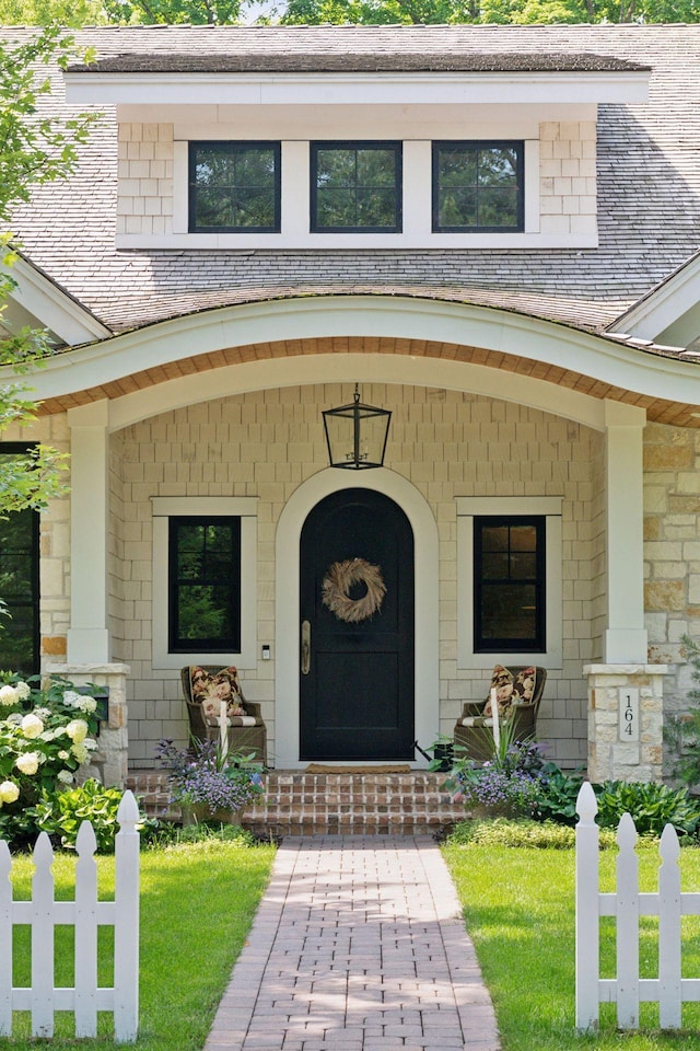 view of exterior entry featuring stone siding and fence