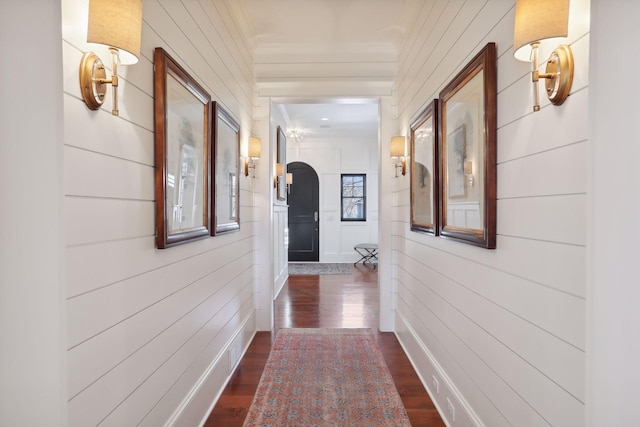 corridor featuring arched walkways, dark wood finished floors, and crown molding