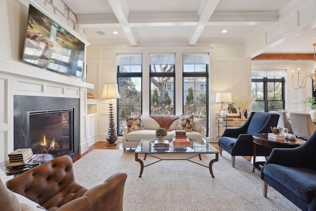 living room with beam ceiling, a glass covered fireplace, and a decorative wall