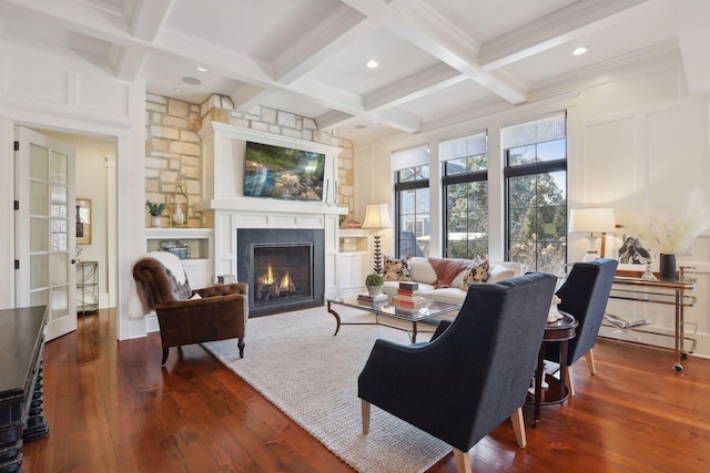 living room featuring beam ceiling, a lit fireplace, hardwood / wood-style flooring, and a decorative wall