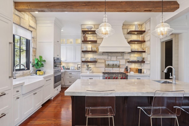 kitchen featuring beam ceiling, custom exhaust hood, open shelves, and a sink