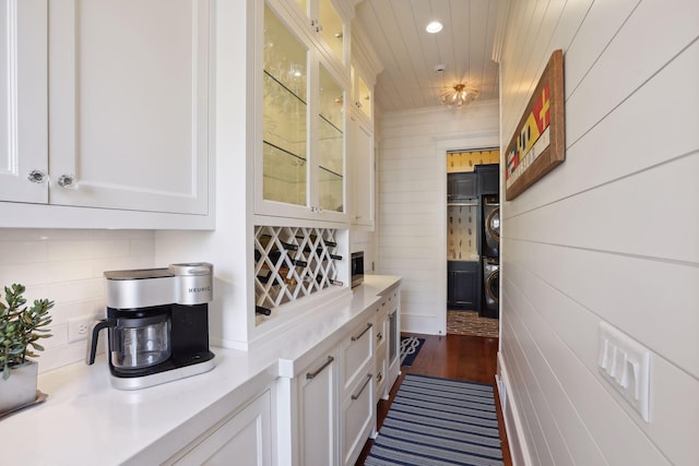 bar featuring dark wood-type flooring, decorative backsplash, recessed lighting, wooden ceiling, and stacked washer and clothes dryer