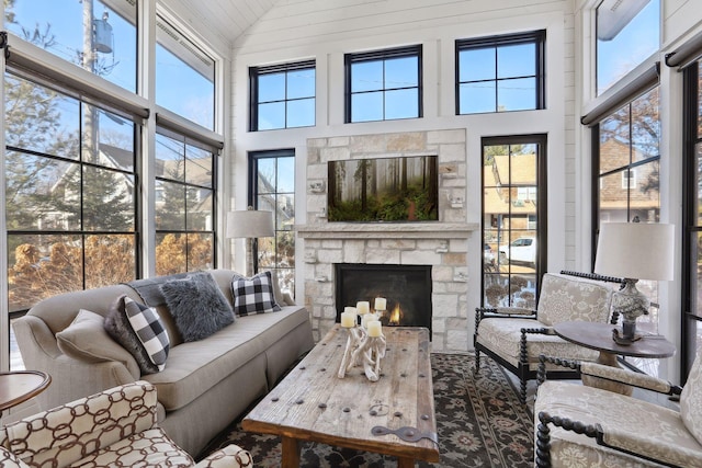 sunroom / solarium featuring a stone fireplace, vaulted ceiling, and a healthy amount of sunlight