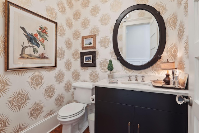 half bath with toilet, vanity, and wallpapered walls