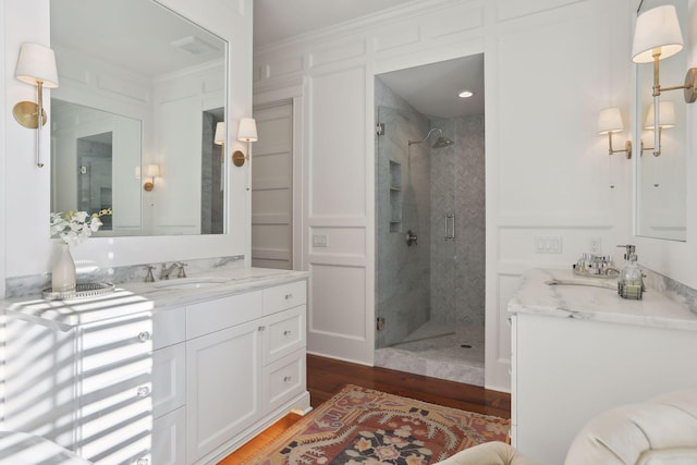 bathroom with vanity, crown molding, wood finished floors, and a stall shower