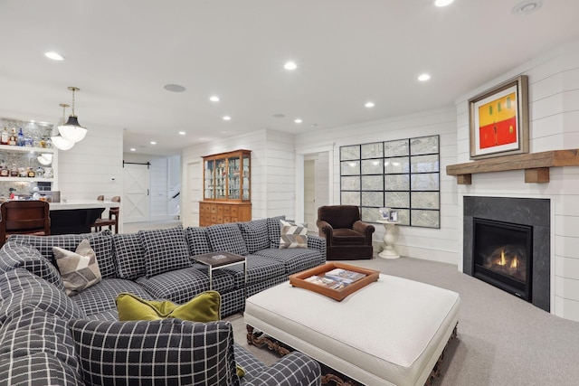 living room with a glass covered fireplace, recessed lighting, a barn door, and carpet floors