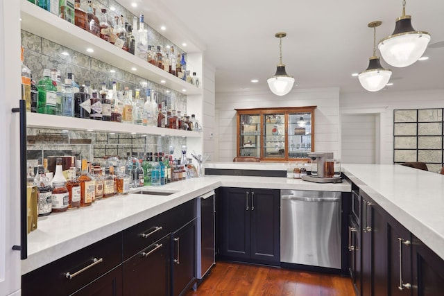 bar featuring dark wood finished floors, a sink, hanging light fixtures, indoor wet bar, and dishwasher