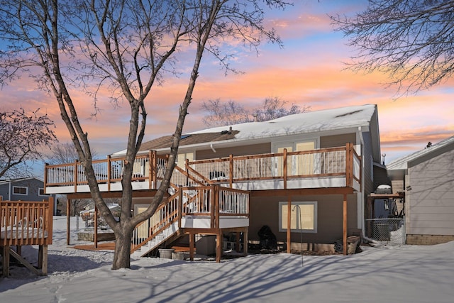 snow covered rear of property featuring a deck and stairs