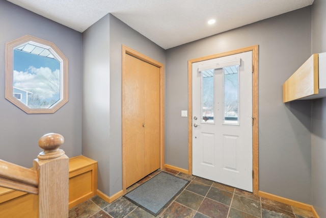 entrance foyer featuring stone finish floor and baseboards