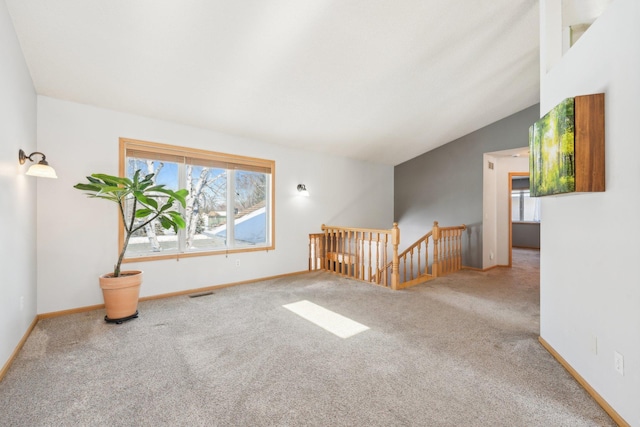 carpeted spare room featuring visible vents, baseboards, and vaulted ceiling