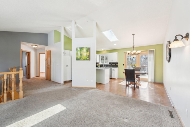 interior space featuring visible vents, light carpet, high vaulted ceiling, a skylight, and a chandelier