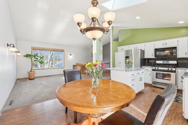 carpeted dining space featuring wood finished floors, baseboards, an inviting chandelier, vaulted ceiling with skylight, and recessed lighting