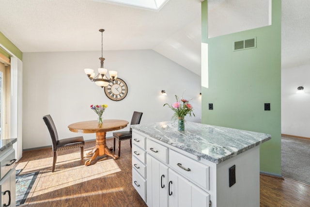 kitchen featuring visible vents, a center island, white cabinets, dark wood-style flooring, and hanging light fixtures