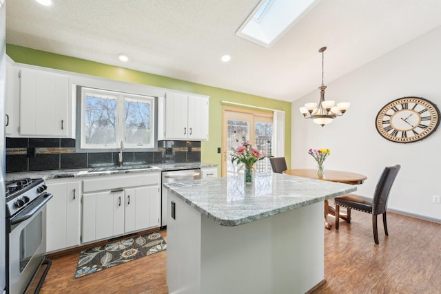 kitchen with wood finished floors, vaulted ceiling with skylight, stainless steel appliances, and a sink