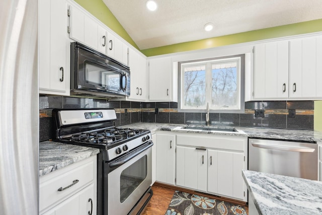 kitchen featuring a sink, decorative backsplash, vaulted ceiling, and stainless steel appliances