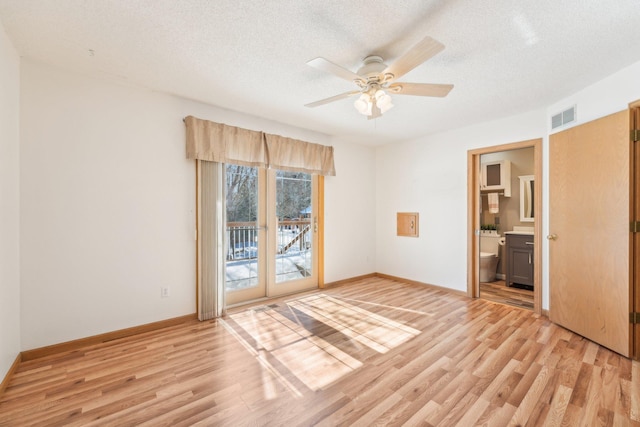 unfurnished room featuring a textured ceiling, visible vents, and light wood-type flooring