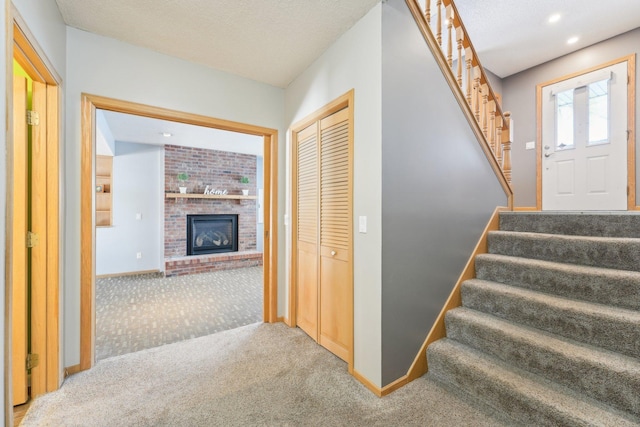 stairs with a textured ceiling, recessed lighting, carpet flooring, baseboards, and a brick fireplace