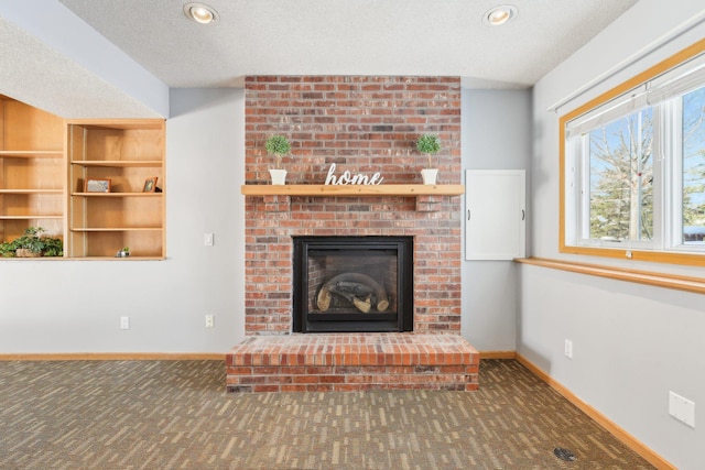 unfurnished living room featuring a brick fireplace, baseboards, carpet floors, and a textured ceiling