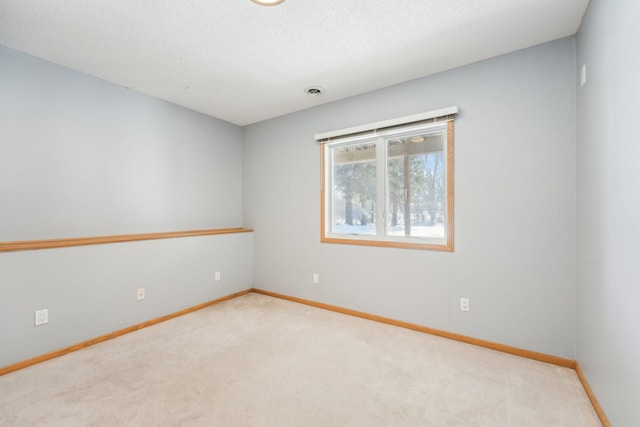 spare room featuring visible vents, carpet, baseboards, and a textured ceiling