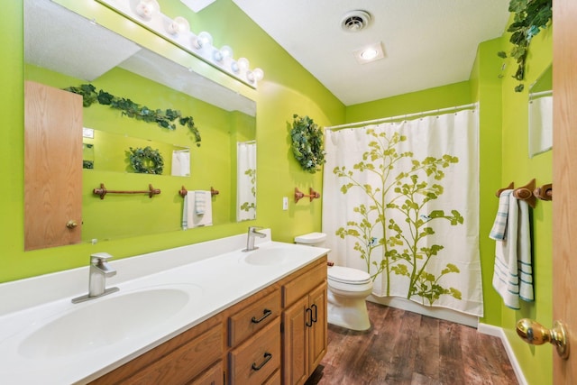 full bath featuring toilet, wood finished floors, visible vents, and a sink