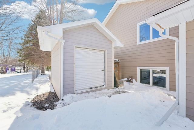 snow covered garage featuring a storage shed and a garage