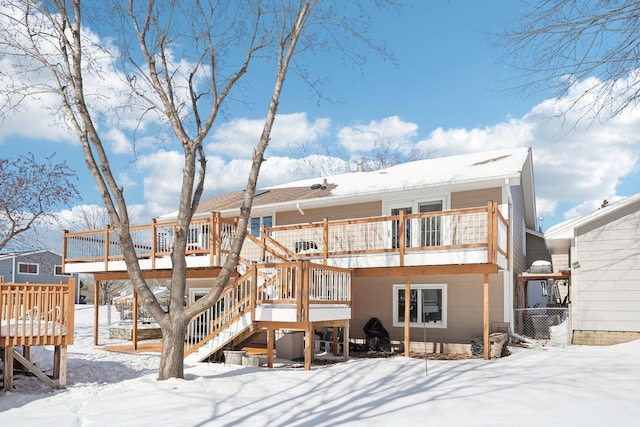 snow covered house featuring a deck, stairs, and fence