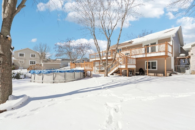 yard covered in snow featuring a deck, stairs, a fenced in pool, and fence