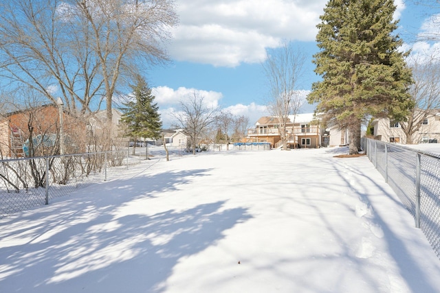 yard layered in snow featuring a fenced backyard and a wooden deck