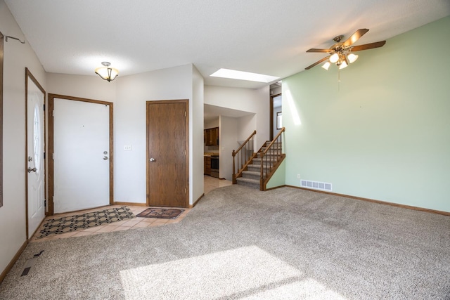 tiled entryway featuring carpet, visible vents, baseboards, a skylight, and stairs