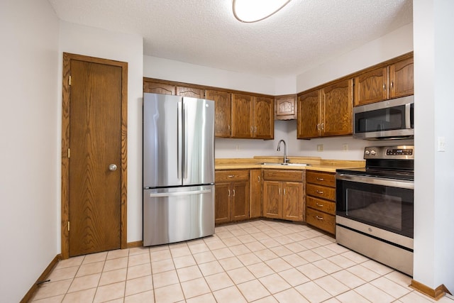 kitchen featuring a sink, light countertops, a textured ceiling, and stainless steel appliances