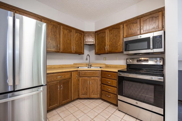 kitchen featuring a textured ceiling, light countertops, appliances with stainless steel finishes, and a sink