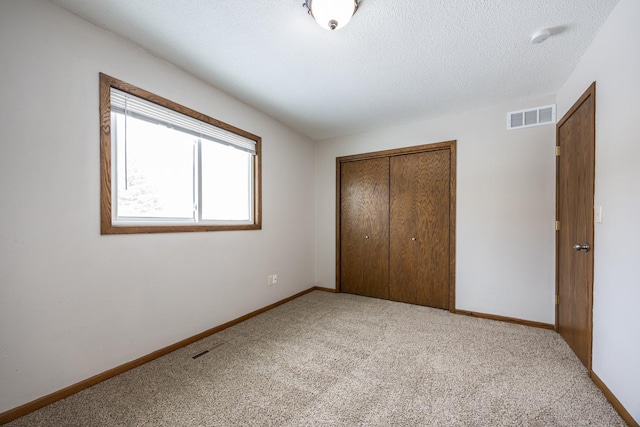 unfurnished bedroom featuring a closet, visible vents, baseboards, and carpet floors