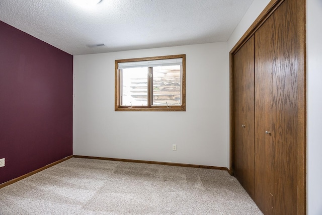 unfurnished bedroom with a closet, baseboards, carpet, and a textured ceiling