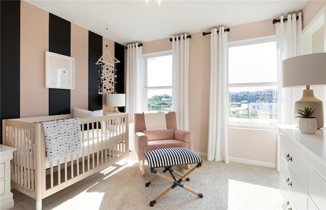 bedroom featuring light colored carpet, a crib, and baseboards