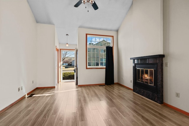 unfurnished living room with a ceiling fan, wood finished floors, visible vents, baseboards, and a tiled fireplace