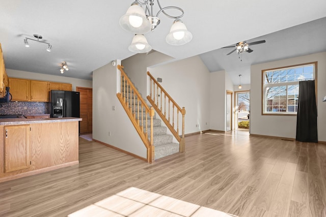 kitchen featuring backsplash, baseboards, open floor plan, black fridge, and light wood-style flooring