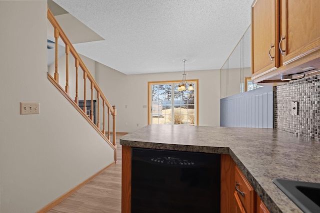 kitchen featuring light wood-type flooring, tasteful backsplash, black dishwasher, a peninsula, and brown cabinetry