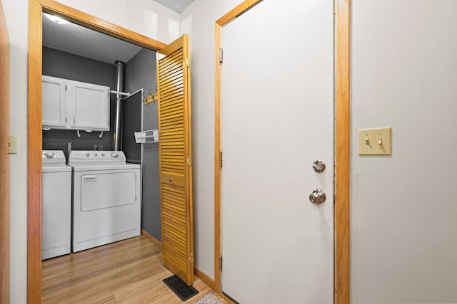 washroom with visible vents, light wood-style flooring, cabinet space, separate washer and dryer, and baseboards