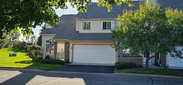 view of front facade featuring a garage, driveway, a front yard, and roof with shingles