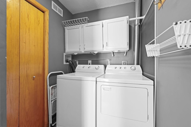 laundry room featuring visible vents, cabinet space, and washing machine and clothes dryer