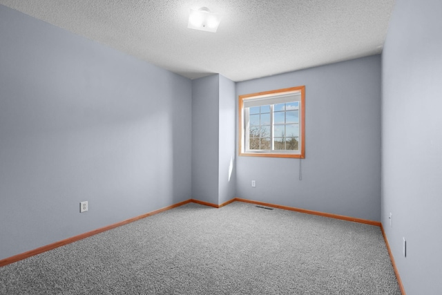 unfurnished room with visible vents, carpet floors, a textured ceiling, and baseboards